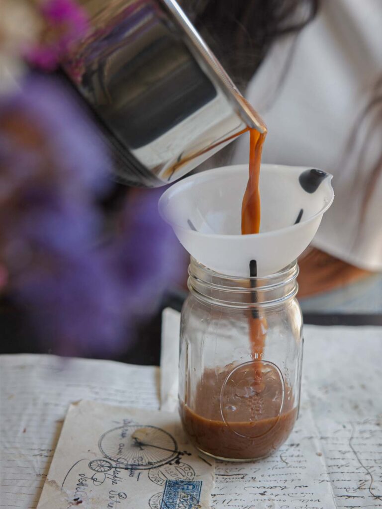 pouring vegan pumpkin spice syrup into funnel and mason jar